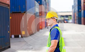 Cheerful factory worker man in hard hat smiling and looking forward with blurred container box background