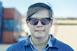 Cheerful factory worker man in sunglasses smiling and looking at camera with joy, Happiness concept