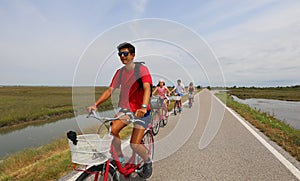 Cheerful family cycling pedals on the bike path near the island