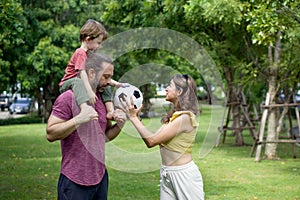 A cheerful family is engaged in a playful soccer match in a lush, serene park, filled with joy and laughter