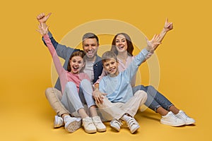 Cheerful Family of Four Celebrating Against a Sunny Yellow Background