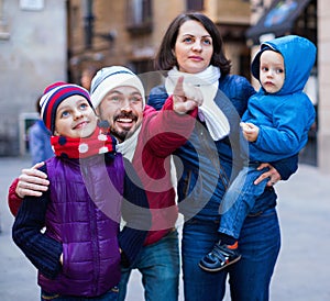 Family of four walking in city and looking showplace photo