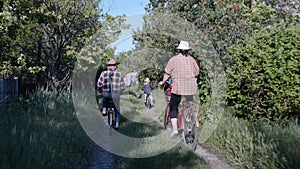 Cheerful family, grandson and his grandmother and grandfather lead an active lifestyle and enjoy joint ride on bicycles