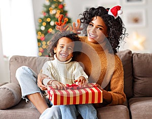 Cheerful family: happy child and mother congratulate each other at Christmas