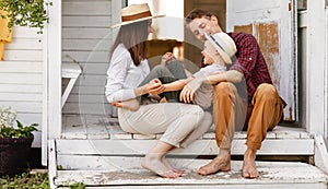 Cheerful family is having a rest and having fun on the porch of a country house