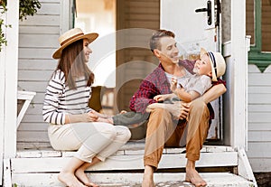 Cheerful family is having a rest and having fun on the porch of a country house