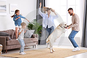 Cheerful family with kids and dog dancing at home