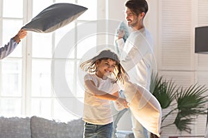 Cheerful family and little daughter play with pillows at home