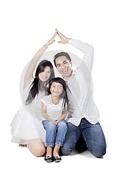 Cheerful family is making house symbol on studio
