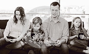 Cheerful family members spending time playing with smartphones