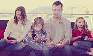 Cheerful family members spending time playing with smartphones