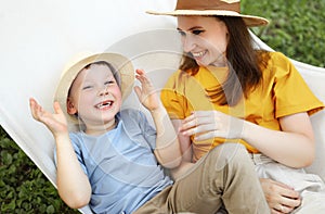 Cheerful family mom and kid boy laugh and play in a hammock in the summer