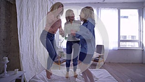 Cheerful family, mother and daughters fun jumping on bed and then hugging together on camera