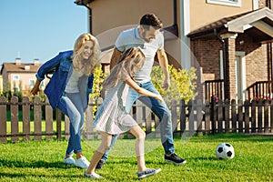 Cheerful family playing football on the backyard lawn