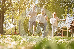 Cheerful family playing with their children`s in the meadow.