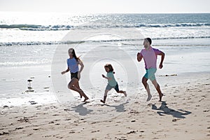 Cheerful family running on the beach. Happy mother father with child son, having fun during summer holiday. Active