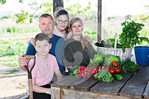 Cheerful family sitting at table in vegetable garden