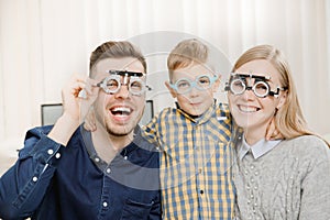 Cheerful family with small child reception doctor ophthalmologist using glasses