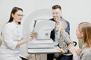 Cheerful family with small child reception doctor ophthalmologist using glasses