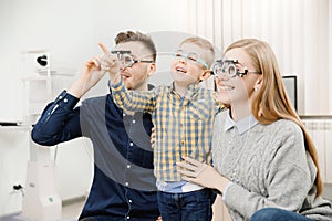 Cheerful family with small child reception doctor ophthalmologist using glasses