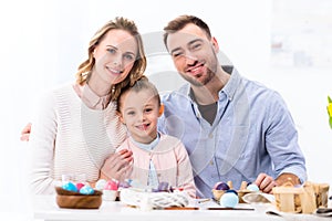Cheerful family smiling by painted eggs