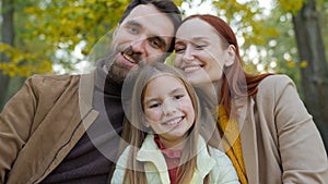 Cheerful family together happy laughing man father woman mother child kid girl little daughter outdoors in park sitting
