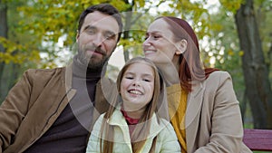 Cheerful family together happy laughing man father woman mother child kid girl little daughter outdoors in park sitting