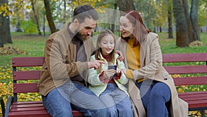 Cheerful family together happy man father woman mother child kid girl little daughter outdoors park on bench dad mom