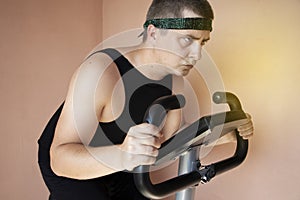 Cheerful fat man in a funny tracksuit is engaged in a stationary bike. The concept of problems with weight, losing weight, playing