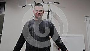 Cheerful fat man performs a wrong exercise in the gym. For the first time in a fitness club.