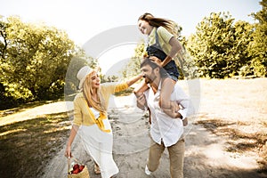 Cheerful father carrying his daughter on shoulders