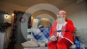 Cheerful Father Christmas congratulating on holiday by smartphone.