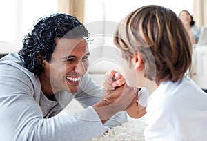 Cheerful father and his son arm wrestling