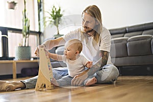 Cheerful father playing with his baby girl on floor at living room