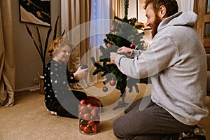 Cheerful father and son decorating Christmas tree at home