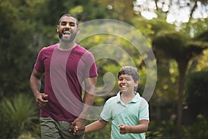 Cheerful father and son holding hands at park