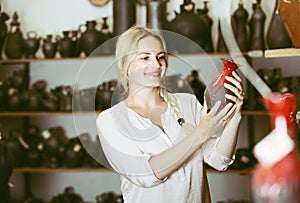 Cheerful female customer picking red glazed crockery