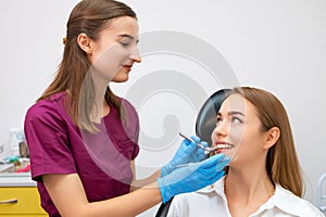 Cheerful female dentist holding dentist tool near smiling young patient
