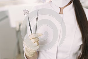 Cheerful female dentist smiling at her office. Beautiful woman student in a protective mask in dentistry stands in the dental