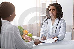 Cheerful female dietologist giving diet plan to client