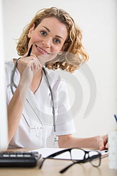 cheerful female doctor sat at desk photo
