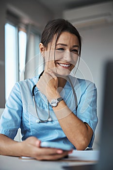 Cheerful female doctor sitting at the table at work