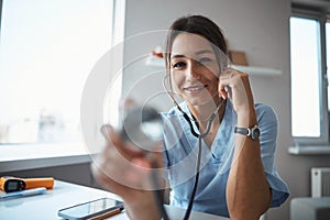 Cheerful female doctor using stethoscope in clinic