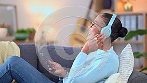Cheerful female enjoying her favorite song or singer phone using headphones. Happy African American woman listening to