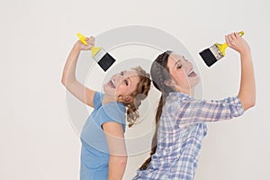 Cheerful female friends singing into paintbrushes