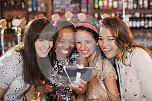 Cheerful female friends taking selfie in pub