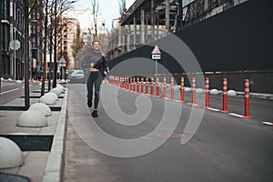 Cheerful female jogger with cornrows running ahead