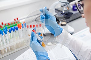 Cheerful female laboratory assistant working with flask