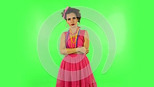 Cheerful female listens attentively and nods his head pointing finger at viewer against green screen