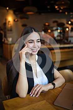 Cheerful female manager talking via cell telephone,resting in cafe